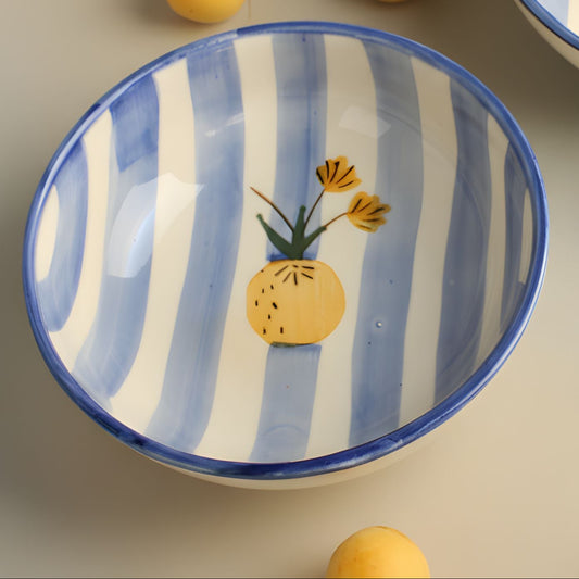 Two ceramic bowls with blue and white stripes and pineapple designs on a surface with lemons.