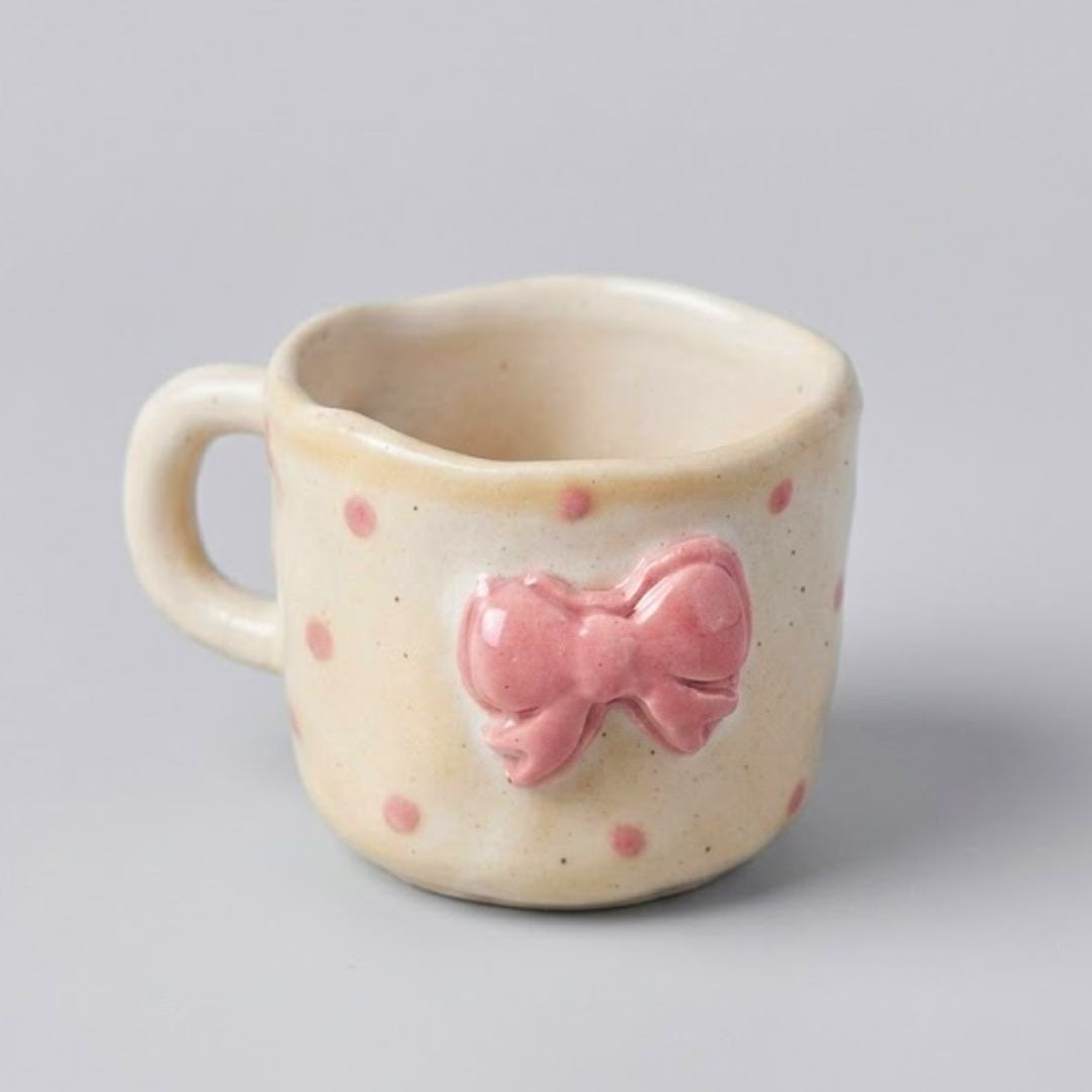 Ceramic mug with a pink bow design on a gray background