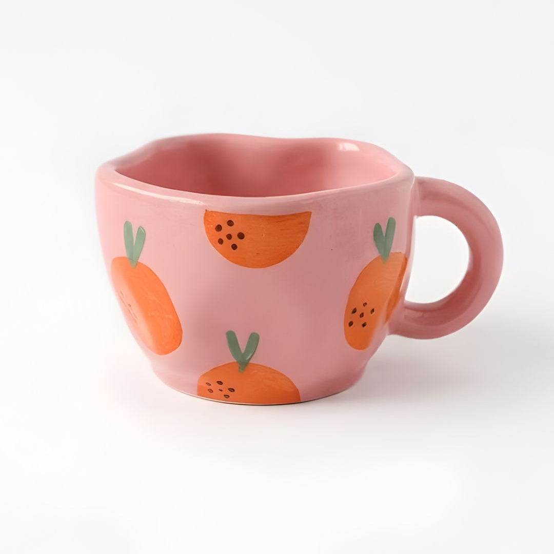 Pink mug with orange and green pattern on a white background