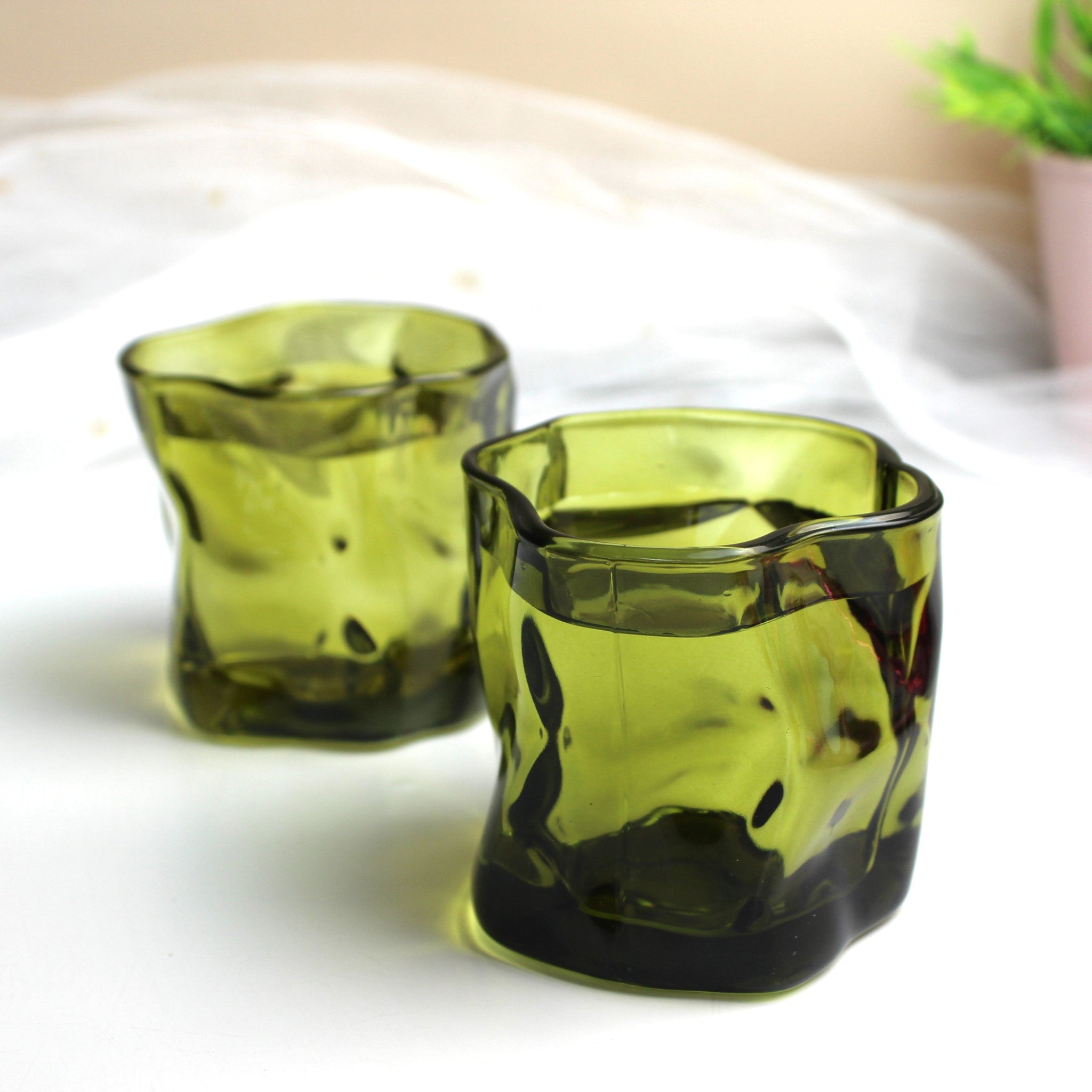 Two green glass candle holders on a white surface