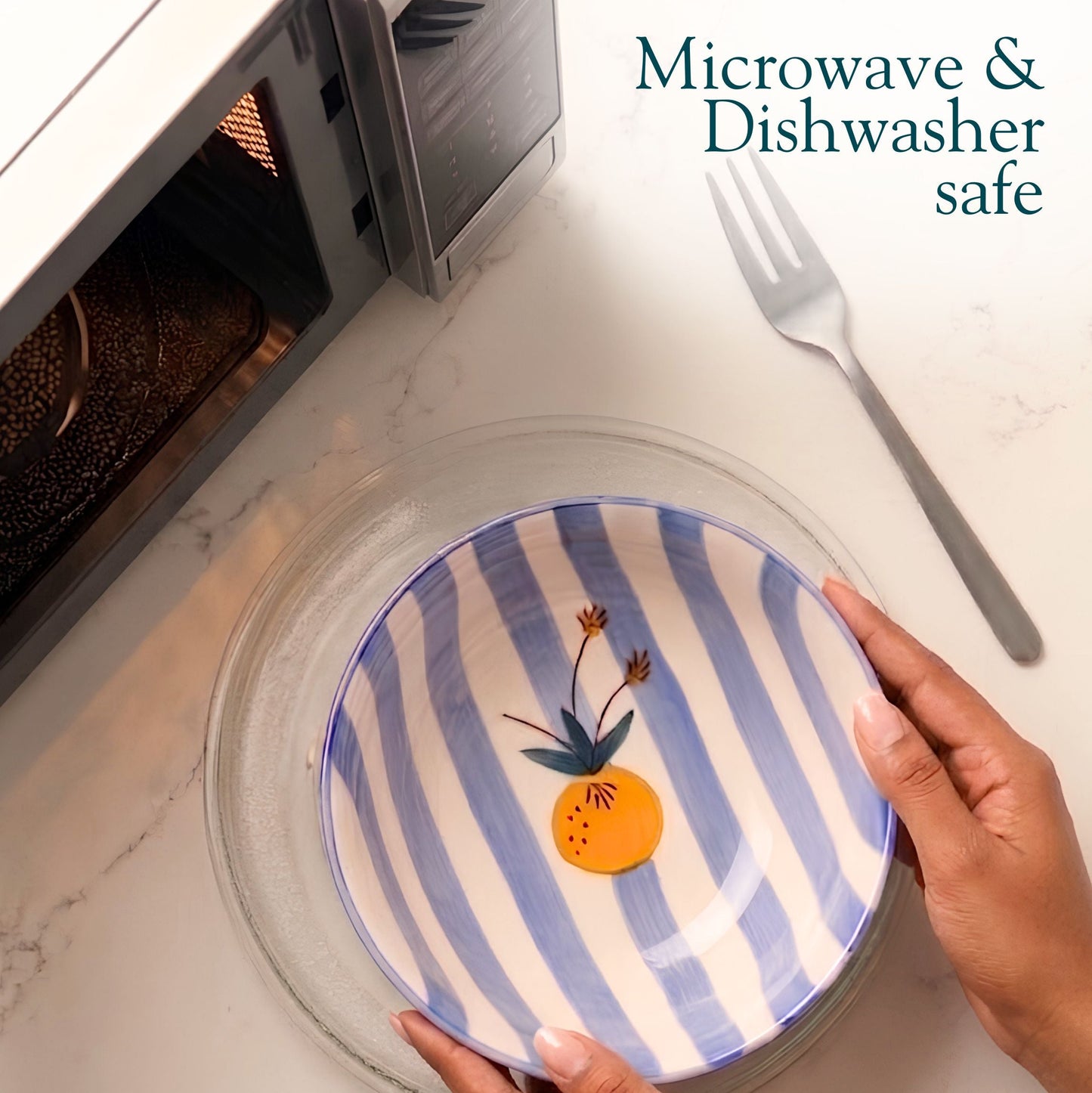 Person holding a blue and white striped plate with floral design near a microwave.