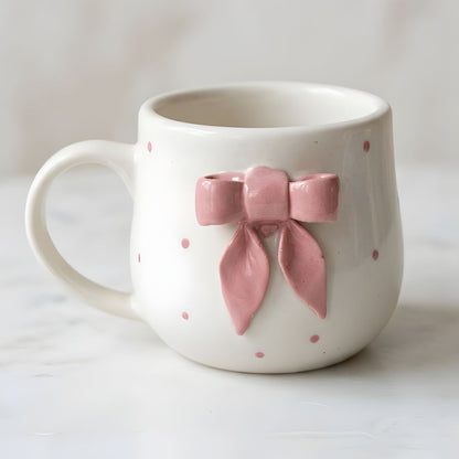 White mug with pink polka dots and a pink bow on a white background