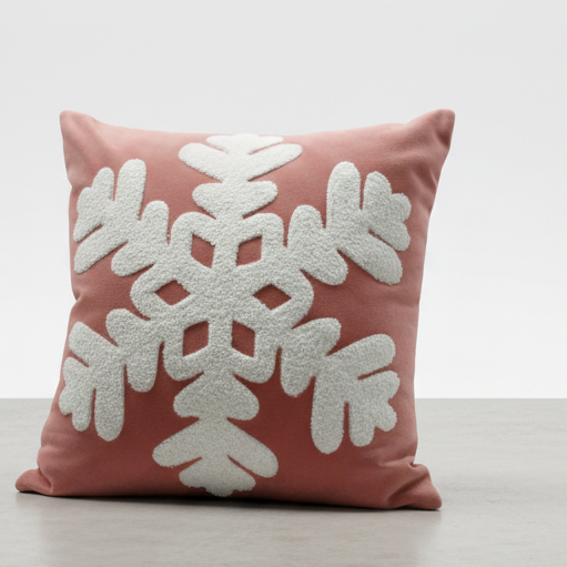 Coral pillow with a white snowflake design on a light gray background