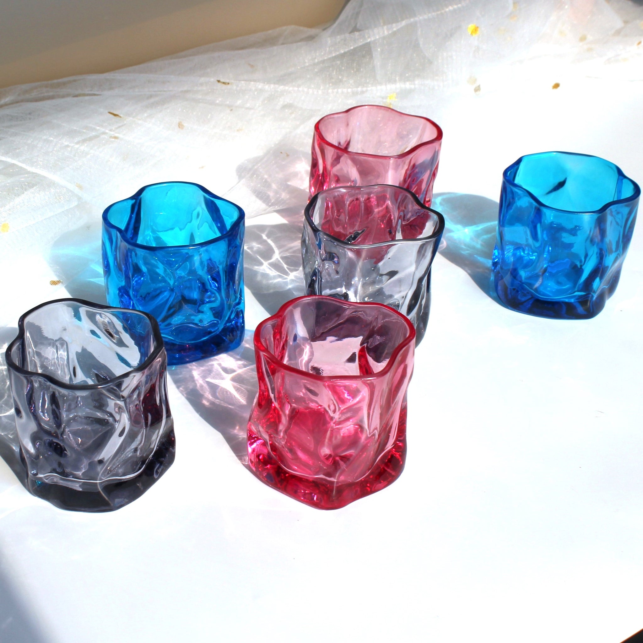 Set of colorful glass tumblers on a white surface