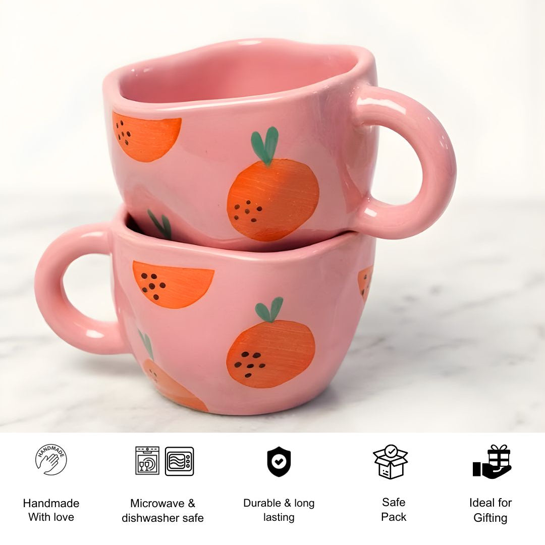 Two pink mugs with orange designs stacked on a white background