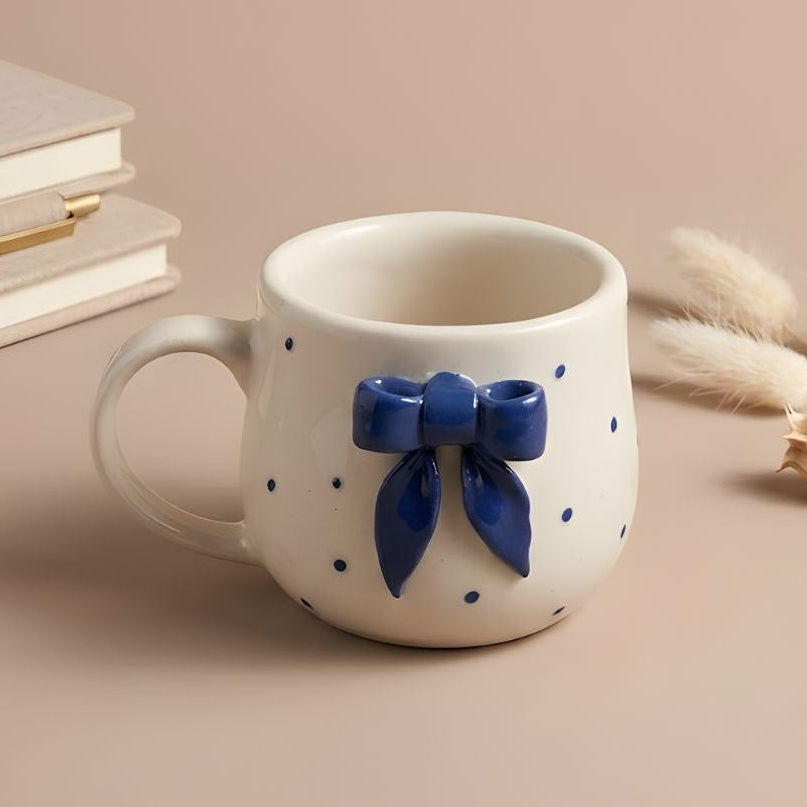 White mug with blue bow design on a beige background