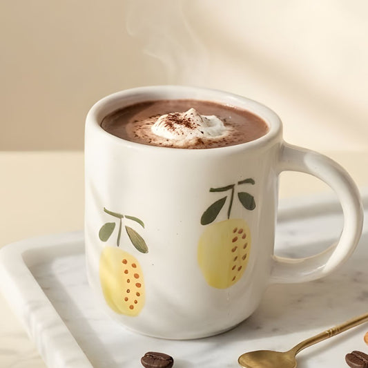 White mug with lemon design filled with hot chocolate on a marble tray.