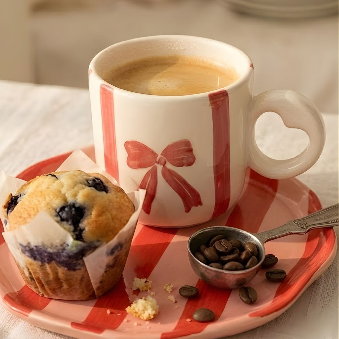 Cup of coffee with a muffin and coffee beans on a checkered plate.