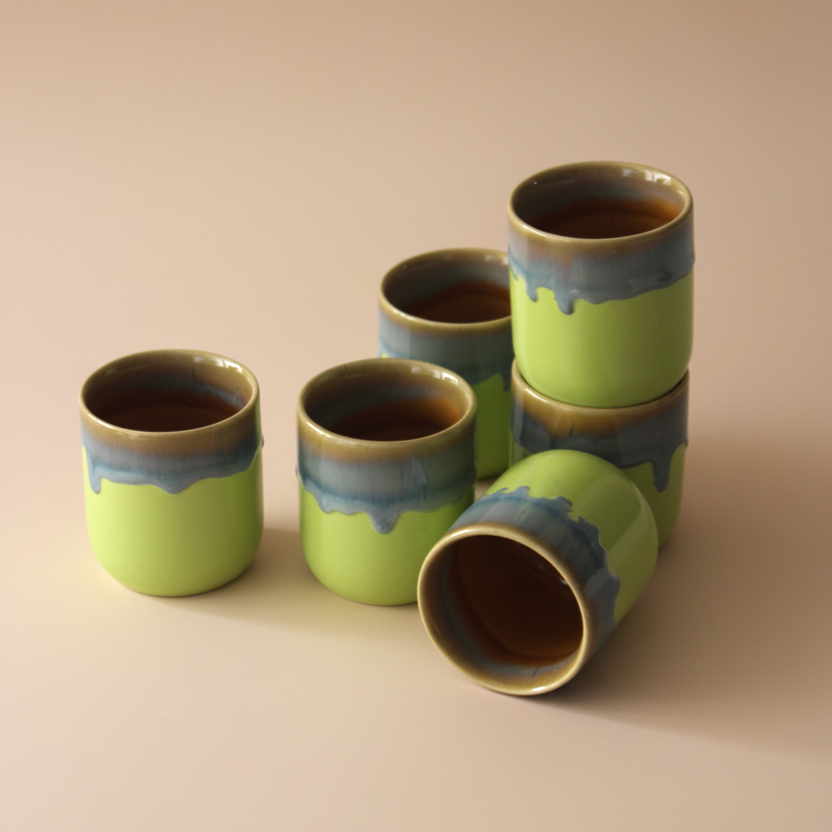 Set of green ceramic cups with brown interior on a beige background
