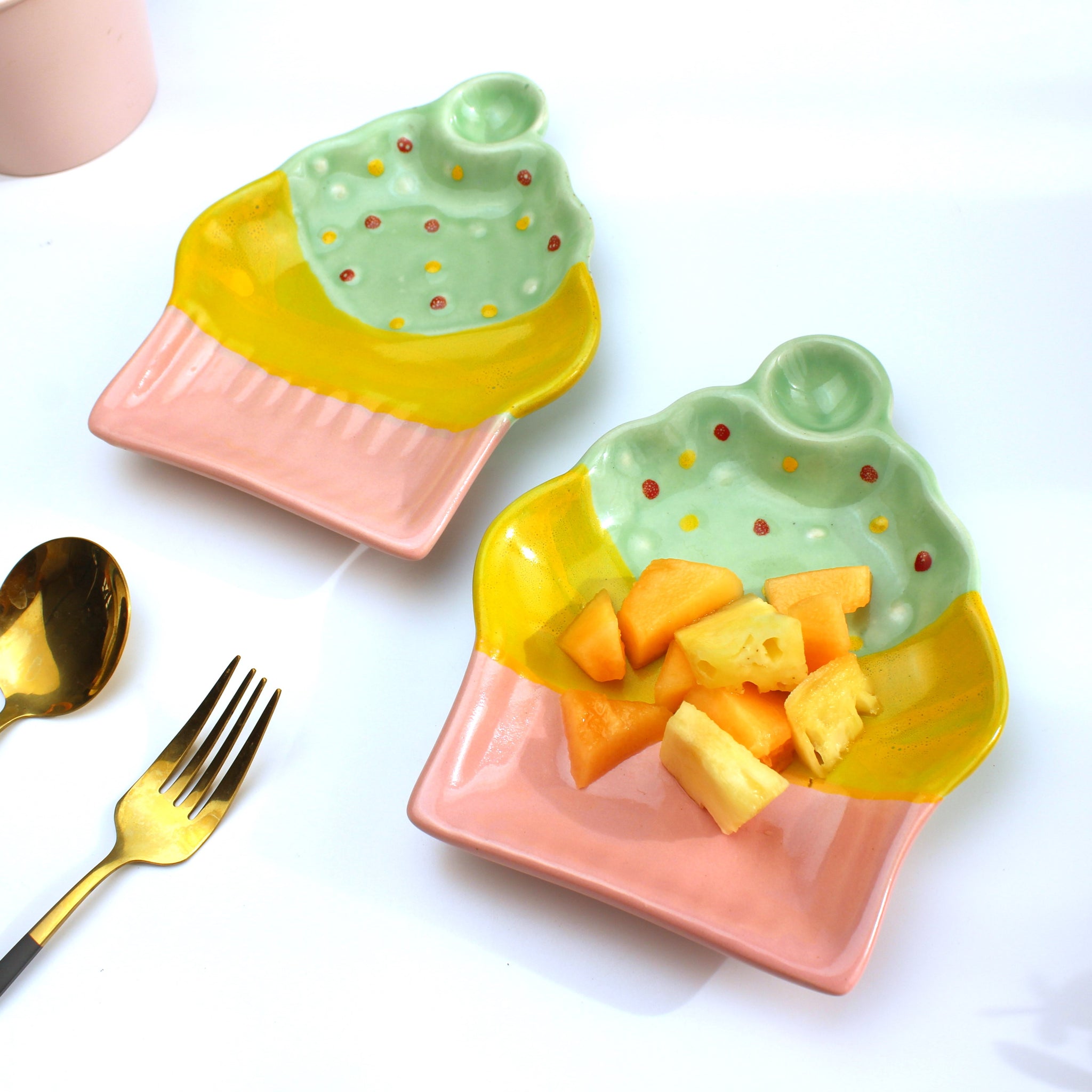 Two ceramic ice cream dishes with fruit on a white background